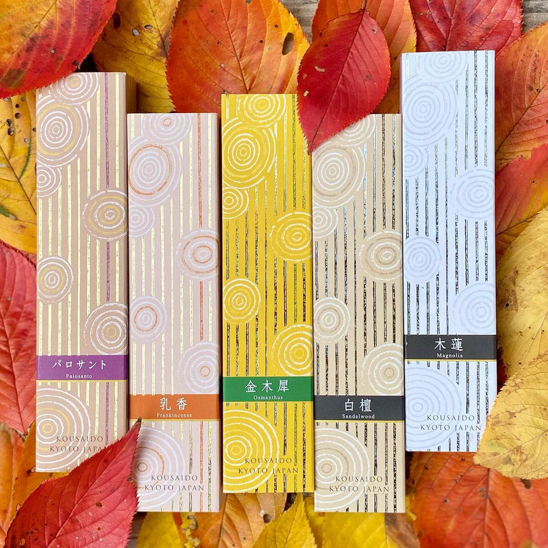 Five Kousaido Hyakurakukou incense boxes - Palo Santo, Frankincense, Osmanthus, Sandalwood and Magnolia - arranged on autumn maple leaves