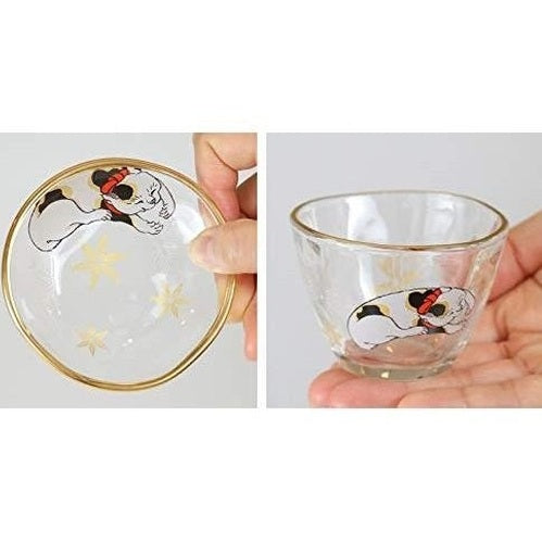 Clear glass sake cup and plate showing calico cat print detail