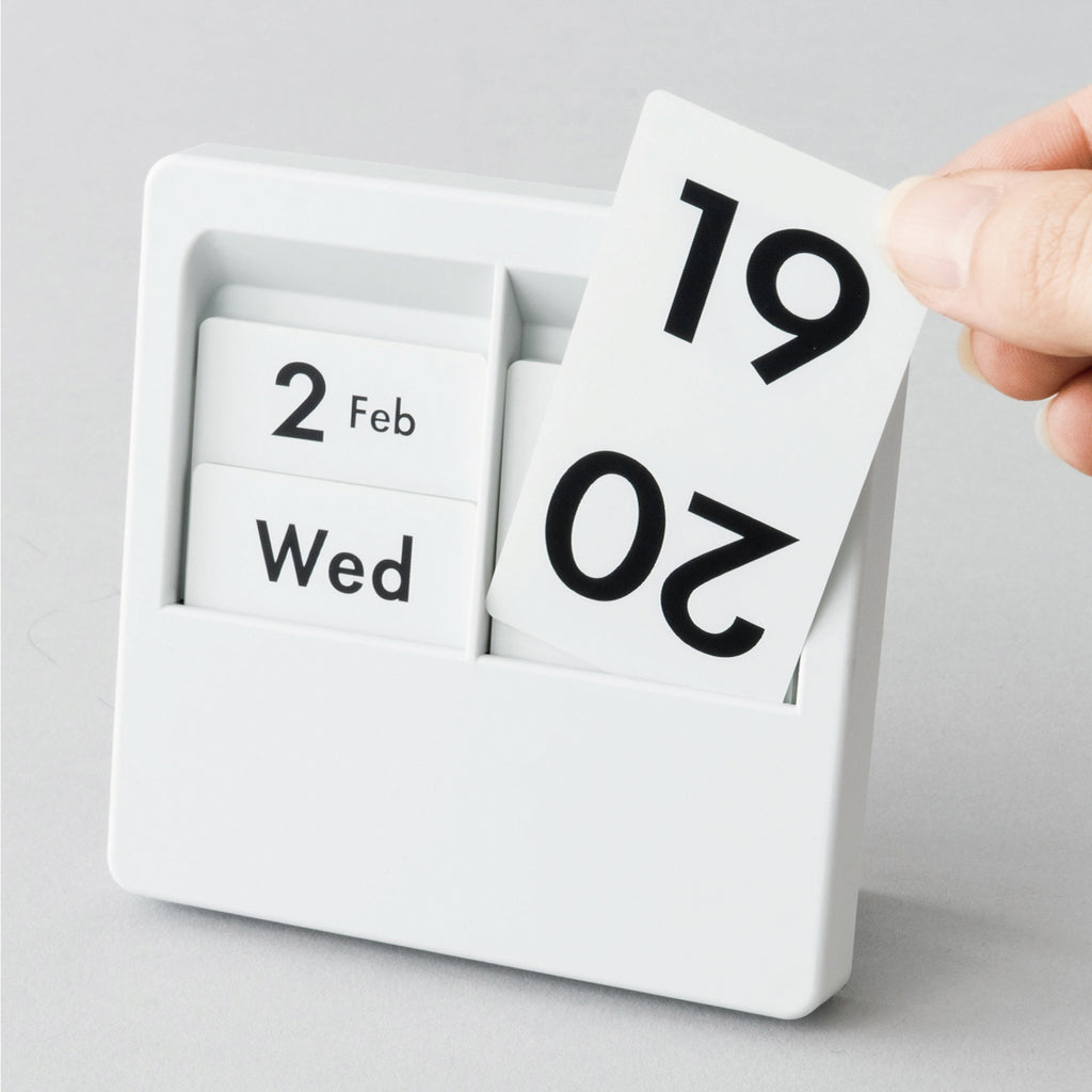Date panel being lifted out of a white Carl Panel Calendar