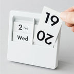 Date panel being lifted out of a white Carl Panel Calendar