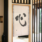 Cream noren curtain with black brushstroke character in light wood frame