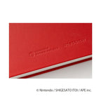 Bottom edge detail of red Hobonichi MOTHER PROJECT embossed on textured fabric cover