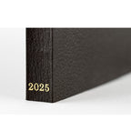 Black textured spine of Hobonichi Techo 2025 planner with gold foil year embossing