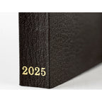 Angled close-up of black Hobonichi Techo 2025 spine showing pebbled texture and gold 2025 text