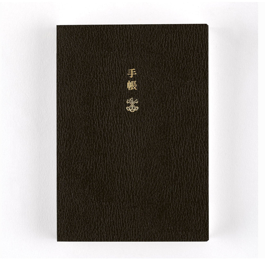 Upright black Hobonichi Techo 2025 planner with pebbled texture and gold foil title text