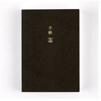Upright black Hobonichi Techo 2025 planner with pebbled texture and gold foil title text