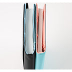 Two Hobonichi Techo 2025 A6 notebooks standing upright showing thread-stitched spines