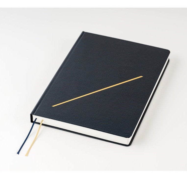 Top-down view of closed navy Hobonichi Techo 2026 A5 planner with gold foil detail and visible white pages