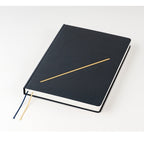 Top-down view of closed navy Hobonichi Techo 2026 A5 planner with gold foil detail and visible white pages