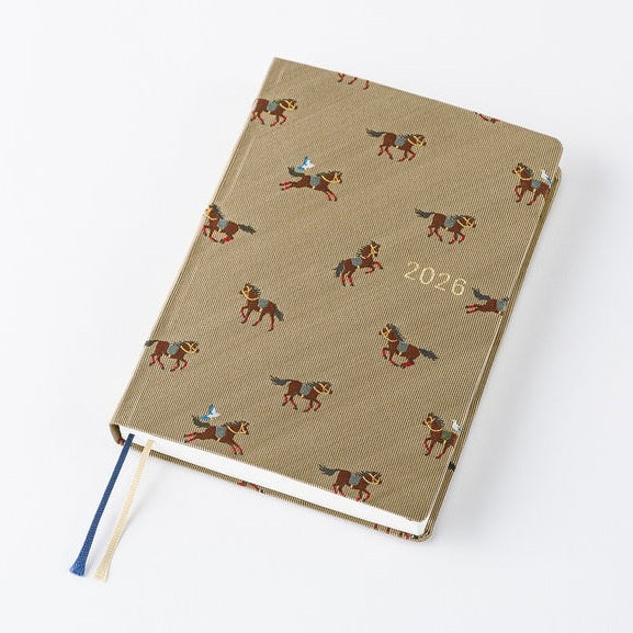 Angled view of closed Hobonichi 2026 A6 diary with galloping horse textile cover