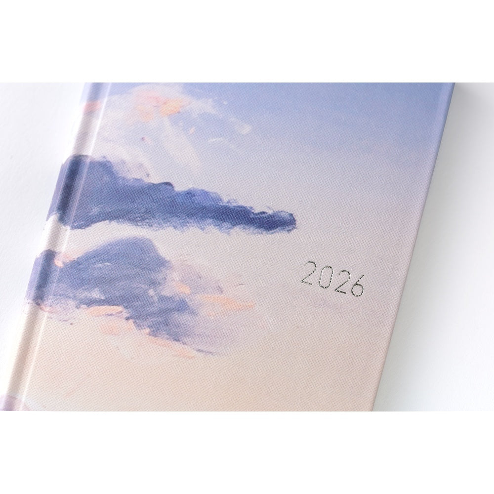 Close-up of Hobonichi Techo 2026 Weeks ENG textured fabric cover corner showing blended blue and peach clouds