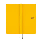 Flat lay of closed Hobonichi Techo 2026 diary showing textured yellow cover and spine detail