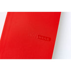 Close-up of raised 2026 MEGA logo on textured tomato red Hobonichi diary cover
