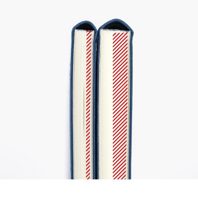 Spines of two Hobonichi planners showing blue fabric edges and red striped page markers
