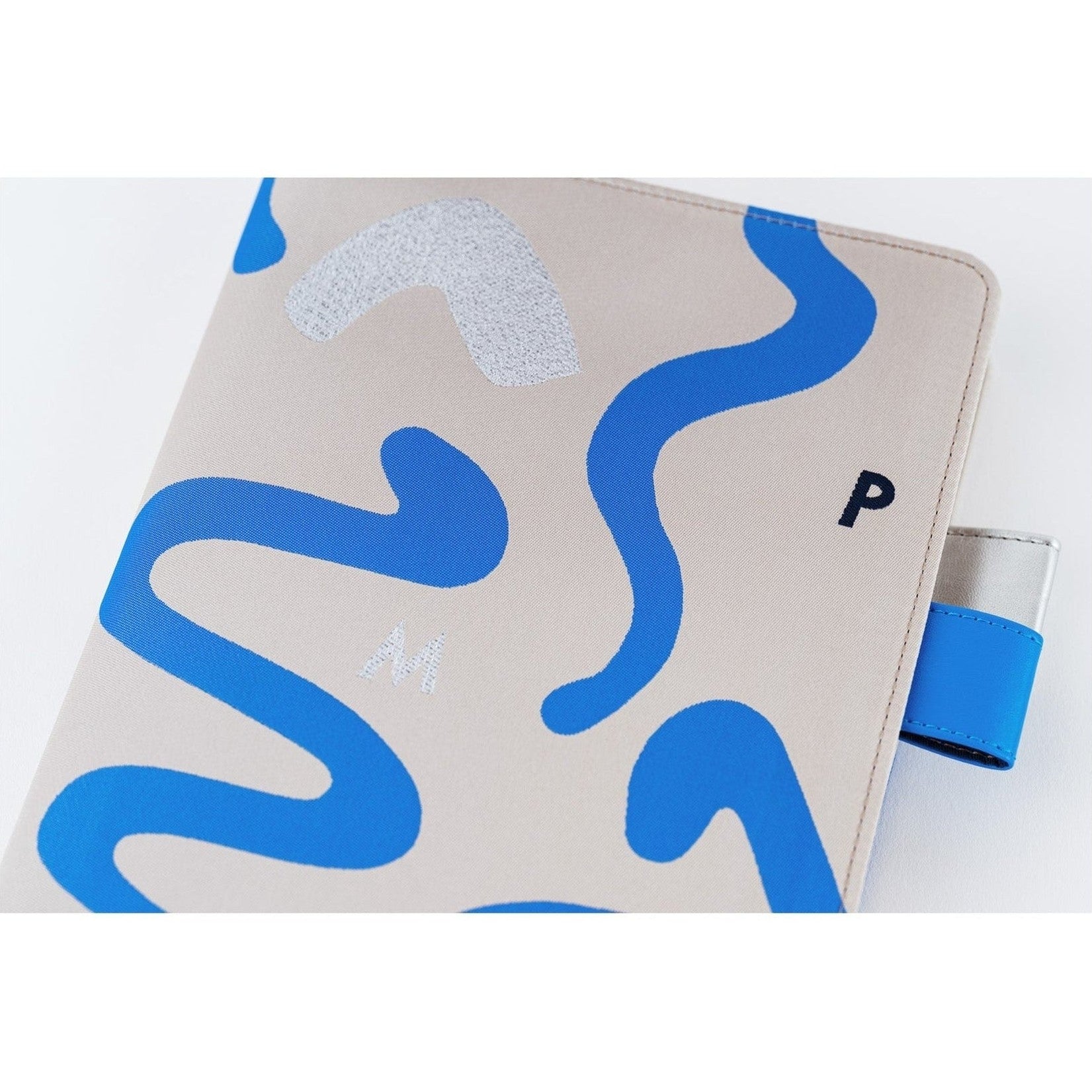 Close-up of textured beige Hobonichi Techo A5 cover with blue wavy lines and silver whitecap detail
