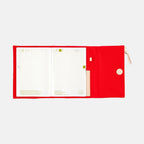 Red Hobonichi Techo A5 Tragen cover holding grid planner with date headers visible
