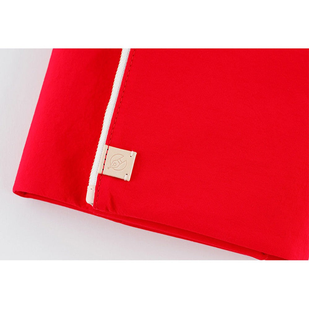 Corner detail of red Hobonichi Techo A5 cover showing zipper seam and embossed logo tag