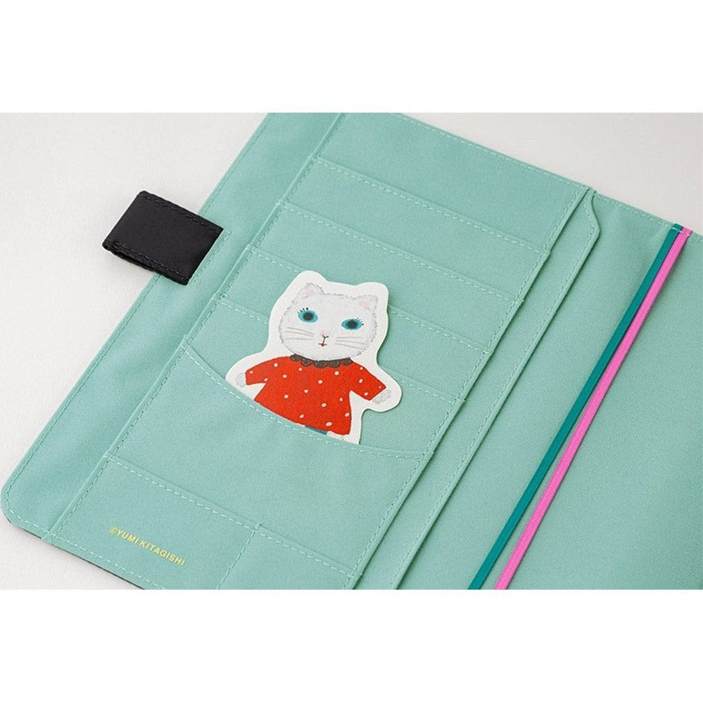 Close-up of mint green pocket in Hobonichi A5 cover featuring die-cut cat sticker and Yumi Kitagishi branding