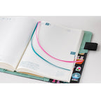 Hobonichi A5 notebook inserted into Yumi Kitagishi Little Gifts cover with grid pages and ribbon markers