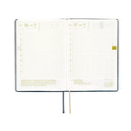 Hobonichi Techo A6 2025 diary open showing gold foil dates and grid layout with ribbon bookmark