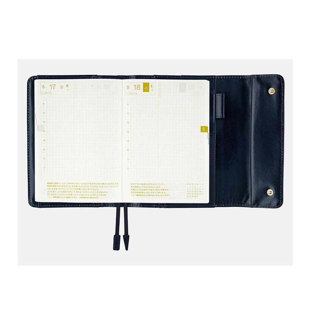 Navy leather cover framing open A6 Hobonichi diary with grid pages and date headers