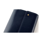 Close-up of deep navy Italian cow leather texture and gold button detail