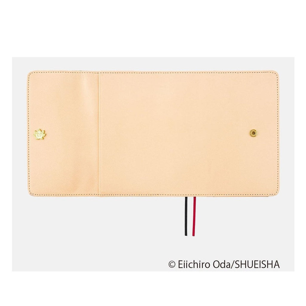 Closed beige Hobonichi Techo A6 One Piece cover featuring gold maple leaf pin and red black bookmark