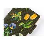 Detail shot of Hobonichi planner cover highlighting yellow tulips and purple pansies on textured fabric