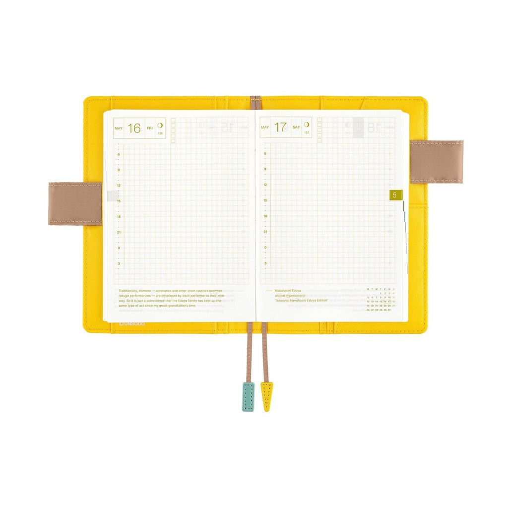 Open Hobonichi Techo A6 planner showing grid daily pages and butterfly pen holders