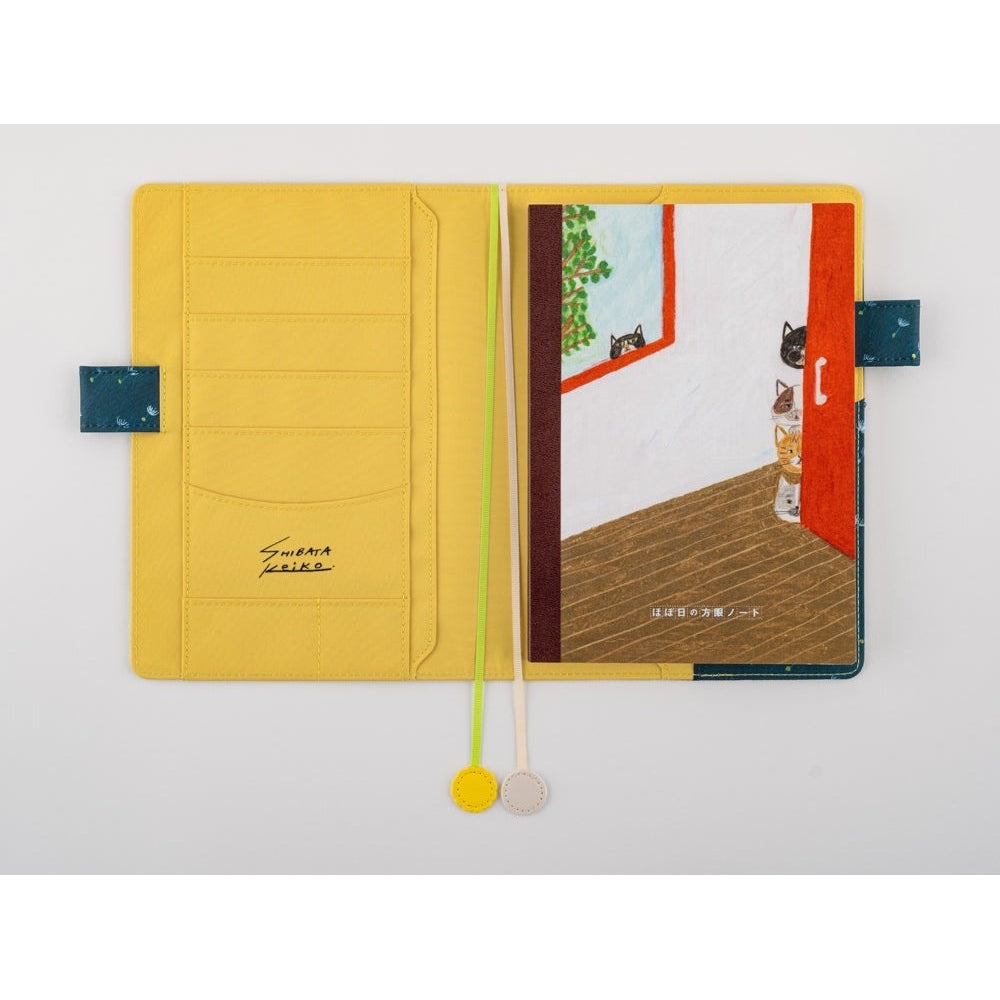 Open Hobonichi Techo notebook showing yellow pockets and ribbon bookmarks