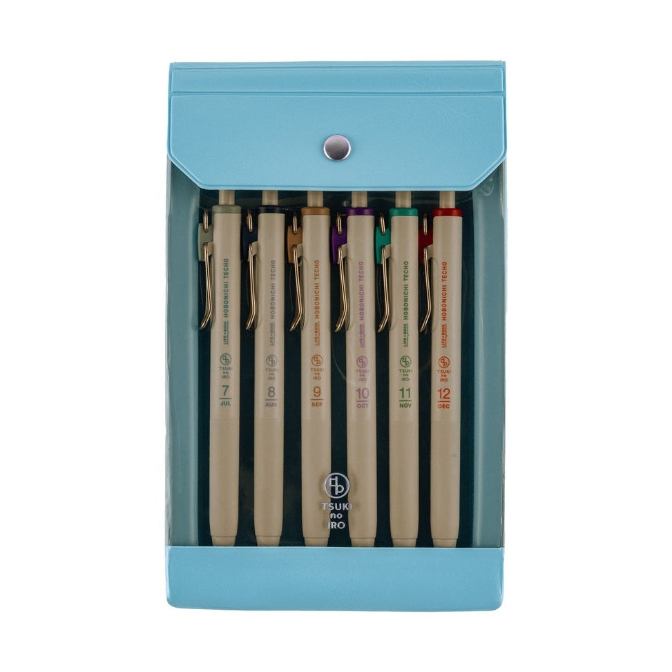 Light blue plastic case holding six Hobonichi TSUKI no IRO pens with gold clips and month labels