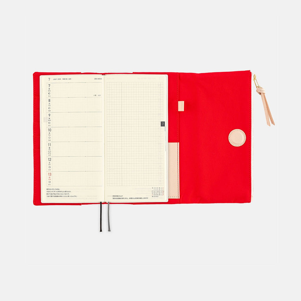 Red Hobonichi cover holding weekly planner with bookmark ribbon