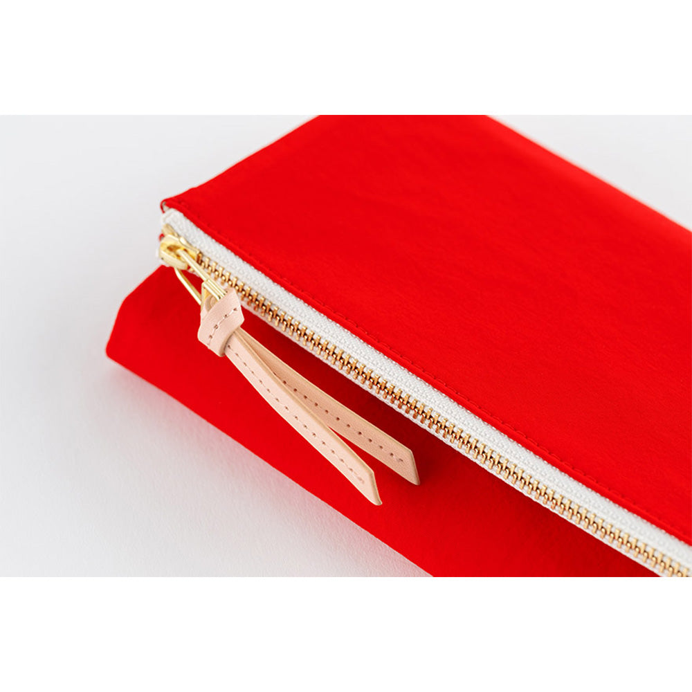 Detail shot of red cover edge with gold zipper teeth and leather pull