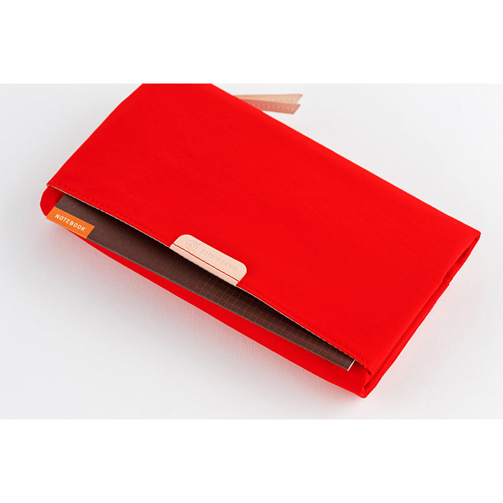 Red tri-fold cover holding brown grid notebook with orange tab