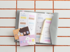 Sticky note cards used as page markers in a grey planner