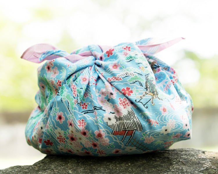 Close-up of Kashiko light blue furoshiki bundle showing detailed gosho-doki furniture print