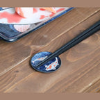 Koi nishikigoi round chopstick rest with chopsticks on a wooden table