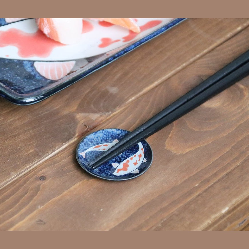 Koi nishikigoi round chopstick rest with chopsticks on a wooden table