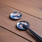 Koi round chopstick rests on a dark wooden table