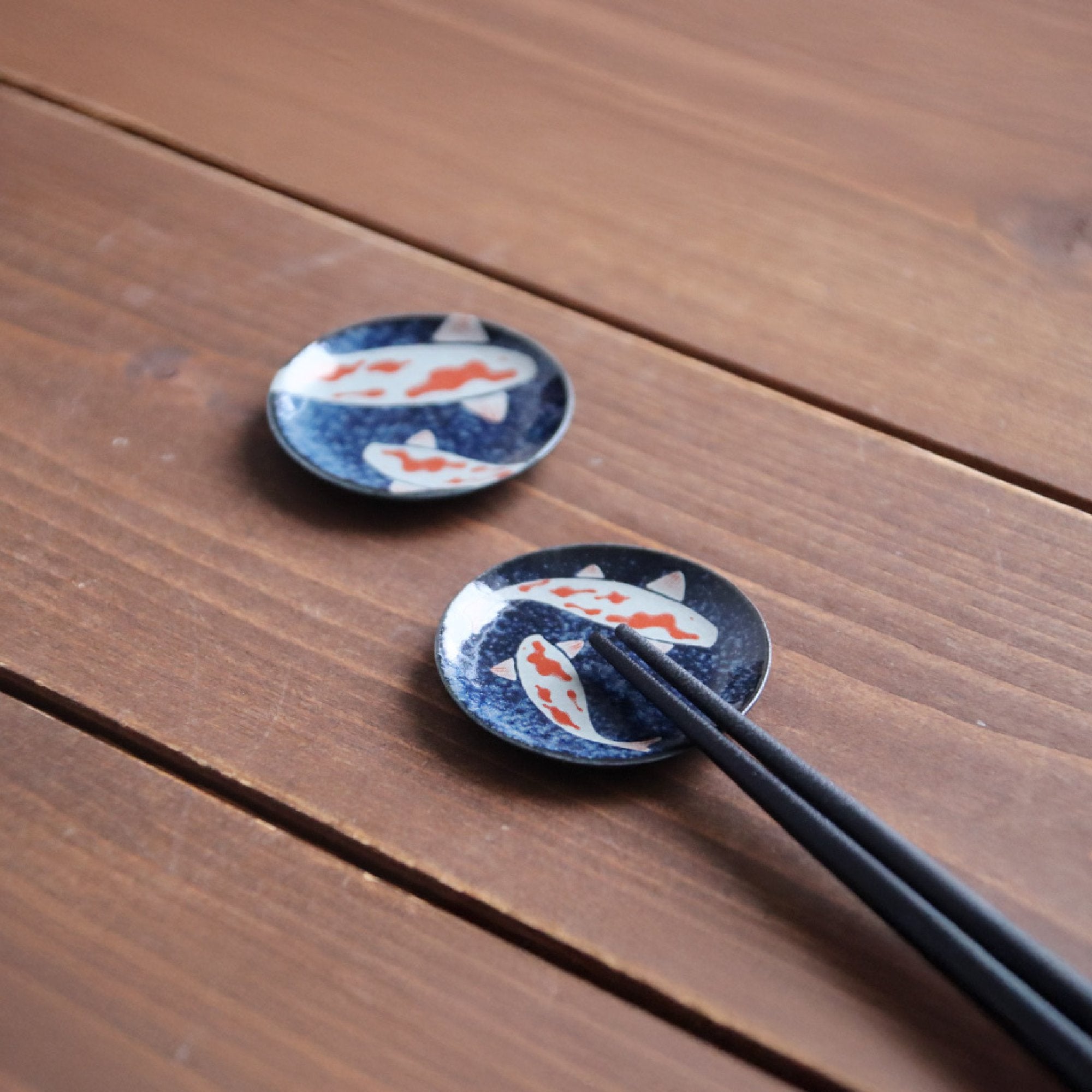 Koi round chopstick rests on a dark wooden table
