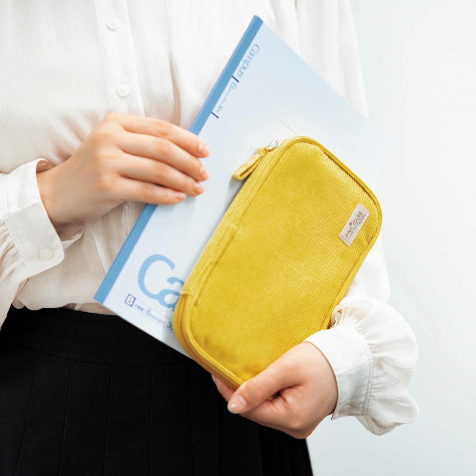 Open yellow corduroy Kokuyo Pancase resting on Campus notebook demonstrating book-like opening