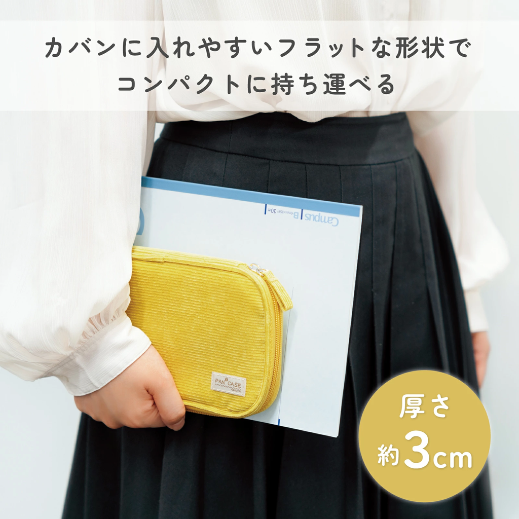Yellow corduroy Kokuyo Pancase held flat next to notebook showing compact 3cm thickness design