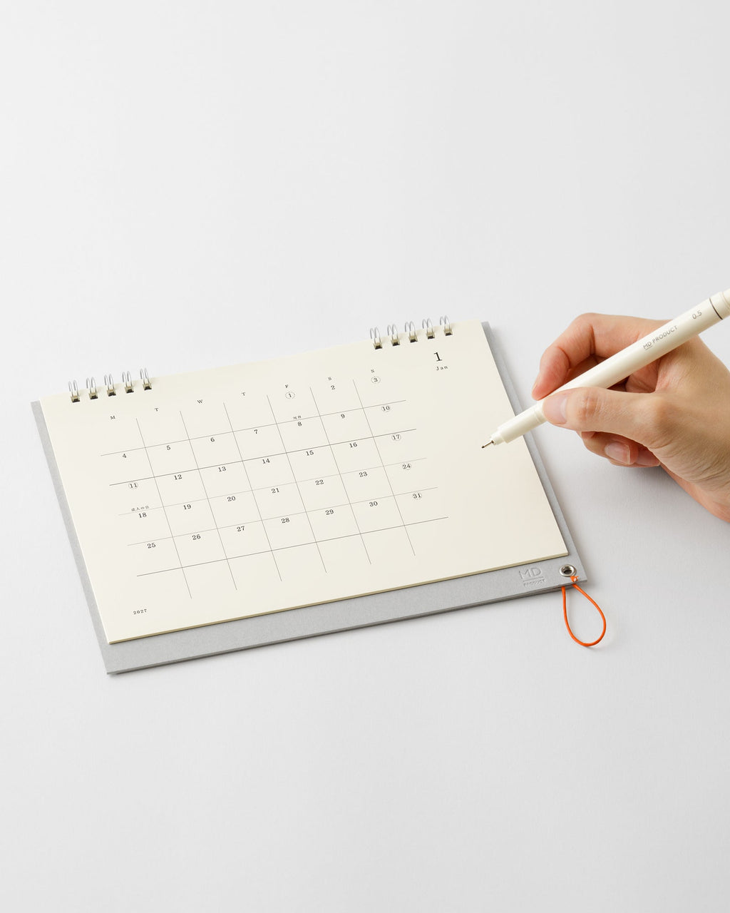 Hand writing on the Midori MD Desk Calendar 2027 folded flat like a notebook