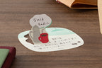 Folded up coffee cup sticky note standing on desk with handwritten message