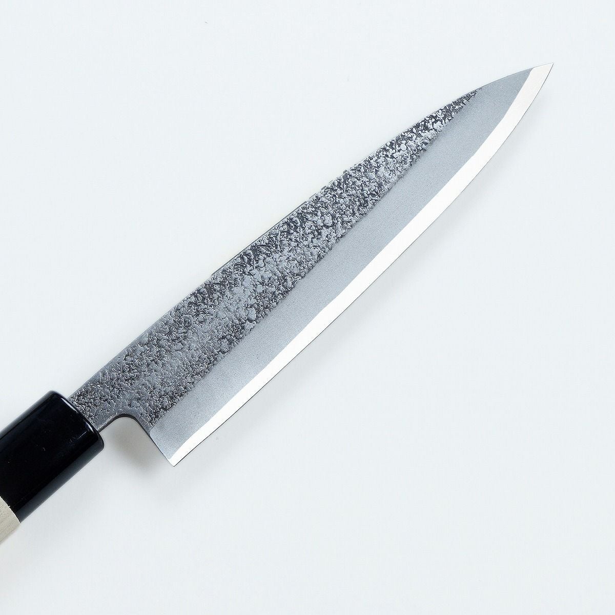 Macro detail of hammered steel and smooth bevel edge on Mikihisa knife