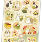 Angled view of textured sticker sheet with rabbit, mochi, and tea party illustrations