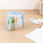 Open light blue accordion file organizer holding receipts on desk