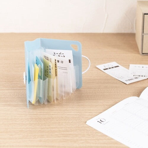 Open light blue accordion file organizer holding receipts on desk