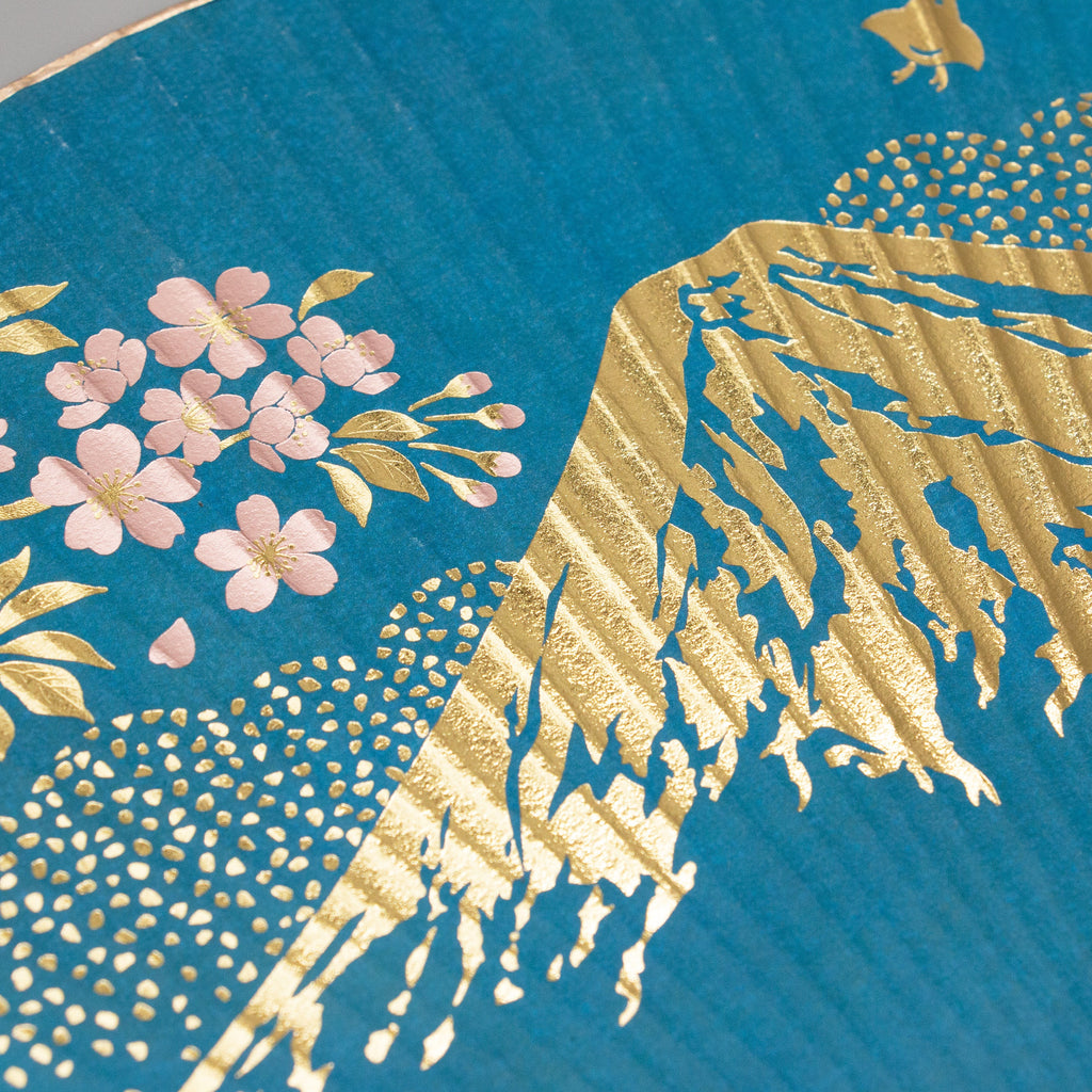 Close-up of blue Miyako uchiwa fan with gold foil Mount Fuji and pink cherry blossom detail