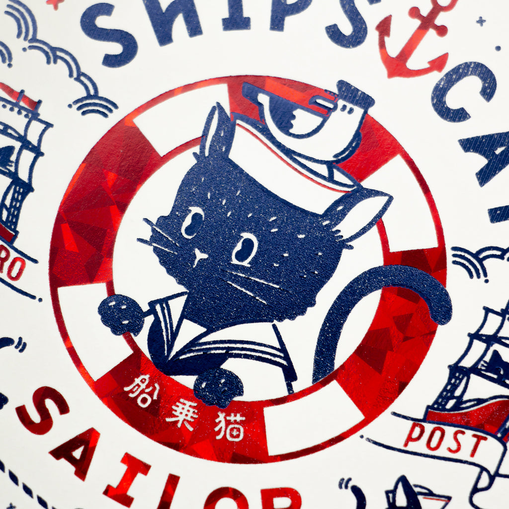 Close-up of foil-stamped sailor cat illustration on die-cut stamp postcard